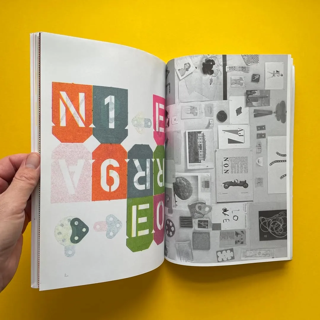 Hands holding open a book spread of collected clippings and photographs against a yellow ground
